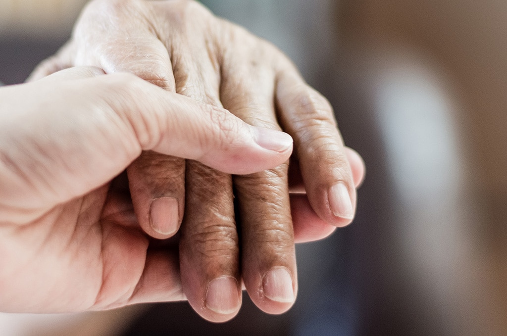 Hospice care resident hold hand with caregiver